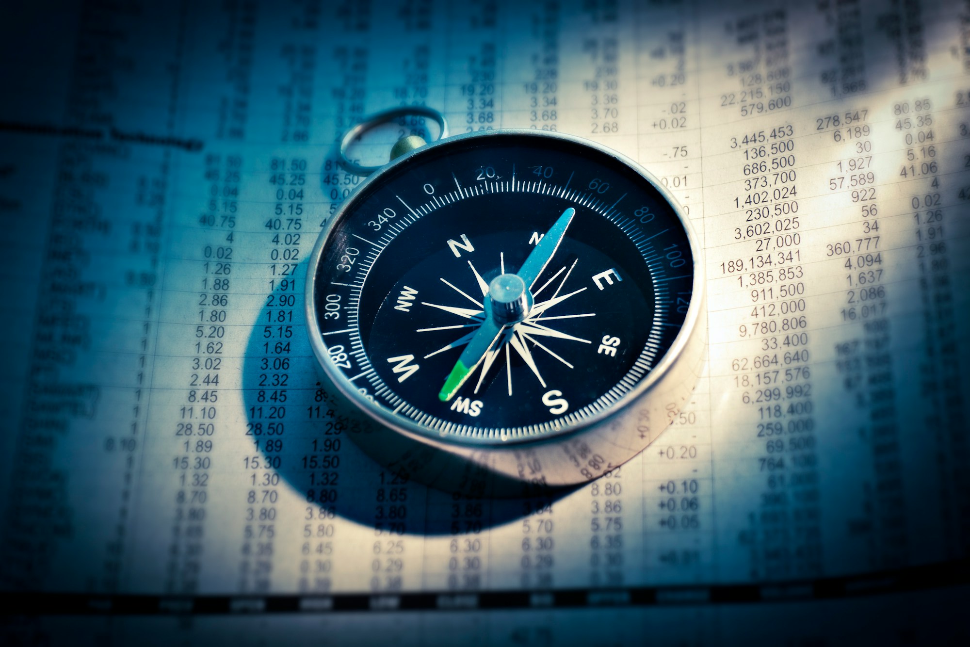 A compass resting on a printed chart in blue light