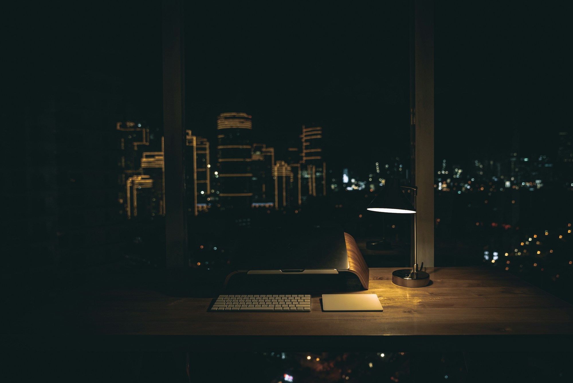 A desk lamp lit over a city at night